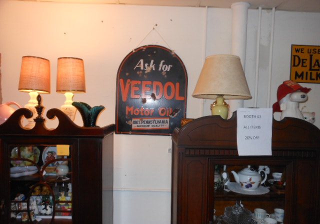 A Veedol advertising sign above an antique cabinet with lamps