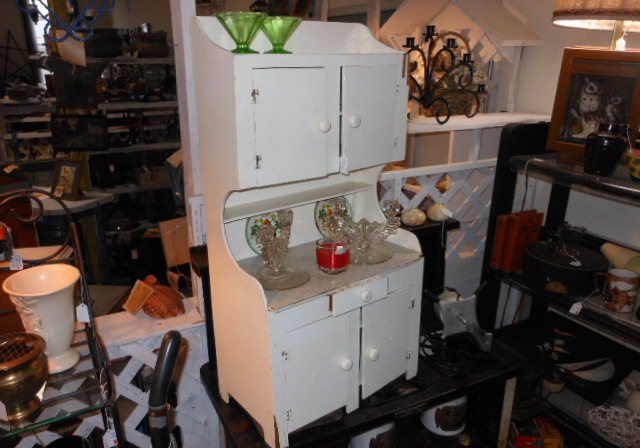 A white kitchen cabinet with glassware and kitchen collectibles