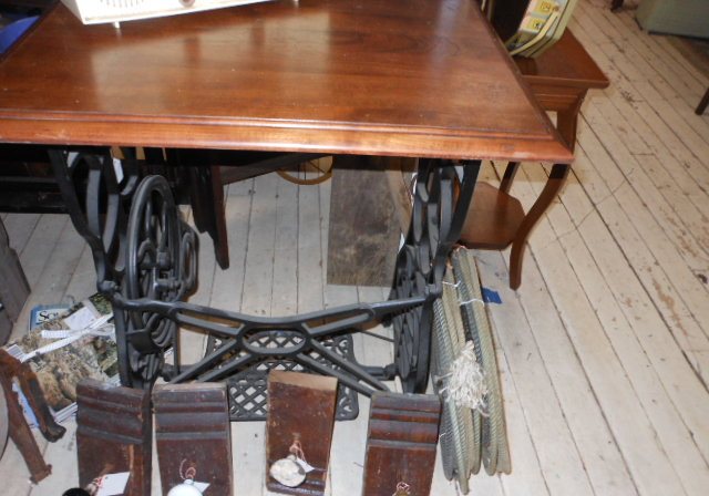 A treadle sewing machine base repurposed as a table with hand tools