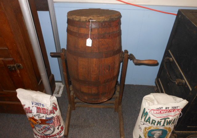 A wooden barrel on a stand beside burlap feed sacks