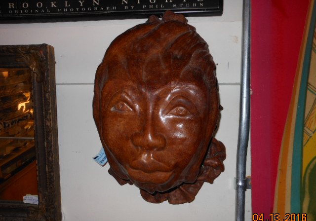 A large carved wooden face mounted on a wall