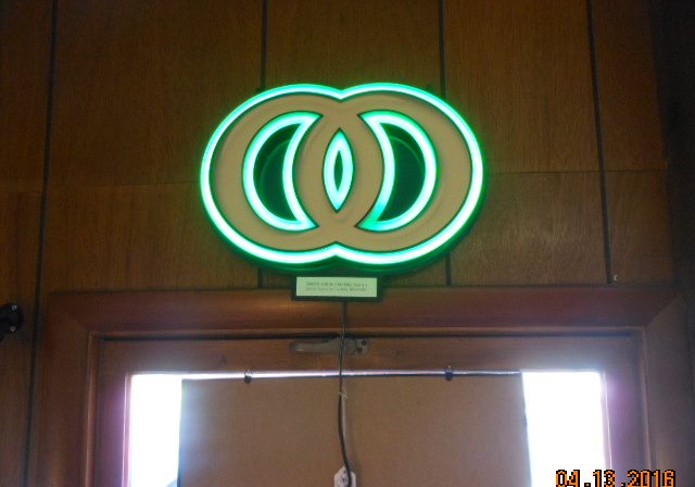 A working neon sign glowing above a wooden door frame