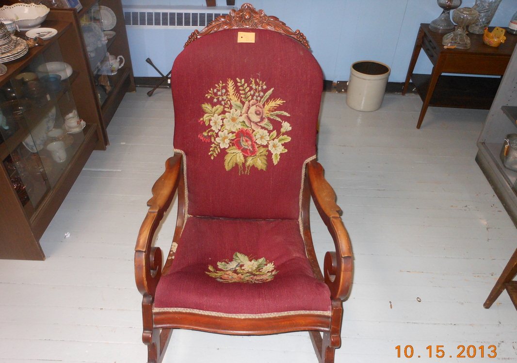 A red upholstered antique rocking chair with a sun motif