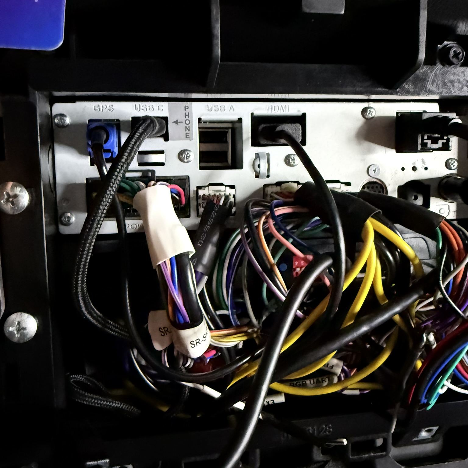 The head unit out of the dash with its wiring and ports exposed
